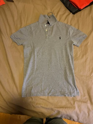 Ljusblå pikétröja från Ralph Lauren - Säljer en stilren piké från Ralph Lauren som är ljusblå (kan se grå ut på bild men är ljusblå? Säljer en grå ifall intresserad) • Storlek: S • Skick: I princip oanvänd • Nypris: 1095 kr • Pris: 750 kr (bud kan diskuteras vid snabb affär) Säljes då den tyvärr inte passar längre. Klassisk modell i ljusblå färg – passar till det mesta och håller hög kvalitet. Perfekt för sommaren. Hör av dig vid frågor eller intresse!
