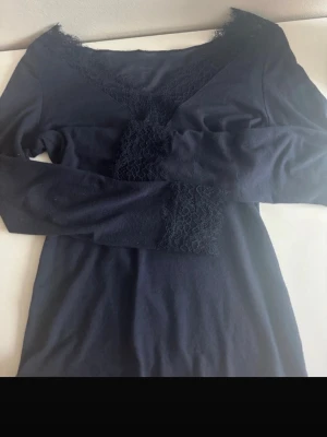 Mörkblå spetsdetaljerad topp - Supersnygg mörkblå topp från Intimissimi med v-ringning och spetsdetaljer längs halsringningen och framtill. Långärmad och i mjukt material med inslag av kashmir för extra komfort. Perfekt för dig som gillar stilrena men ändå unika plagg.