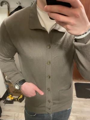 Stickad merinoull cardigan - Otroligt fin brun/beige stickad merinoull cardigan från John Henric. Modellen är 180cm, 75kg