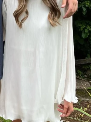 Vit kort klänning med volangärm - Säljer en söt vit kortklänning med volangdetaljer vid ärmslut och nederkant. Klänningen har långärmade, lätt transparenta ärmar och är gjord i ett tunt, plisserat material som ger ett luftigt intryck. Perfekt för sommarens alla tillfällen!