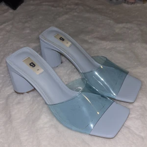 Blå transparenta pumps från Gina - Säljer ett par trendiga pumps från Gina med bred klack och fyrkantig tå. Skorna är ljusblå med transparent plast över foten och har en modern design som sticker ut. Perfekta för dig som gillar stilrena och coola skor.
