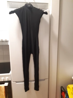 Bodssy Semhar jumpsuit, storlek XXS - Bodssys populäraste jumpsuit Semhar med hög hals och öppning i ryggen. Svart, helt ny etiketter fortfarande kvar. Inga slitningar eller hål.  Finns 3 storlekar, XXS, XS och S. Alla är nya med etiketter.  Material: Modal 90% och elastane 10% . Dubbelsydd.  Ett otroligt skönt och stilrent plagg att ha på sig.