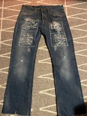 Blå slitna jeans - Riktigt feta blå jeans från Lee med raka ben och tydliga slitningar och hål på framsidan.