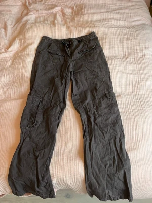 Gråa cargobyxor - Gråa cargobyxor som är raka/vida. Har flera fickor och går att justera i midjan