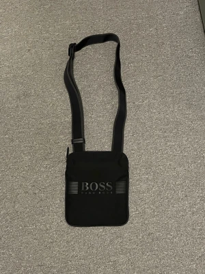Hugo Boss - Snygg svart axelväska från Hugo Boss. Väldigt lite använd. Hör av er vid frågor! 