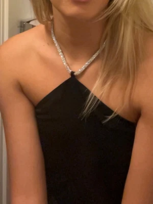 Svart halterneck topp med glitter - Hej!☀️Säljer en snygg svart halterneck topp med minimalistisk design från H&M. Toppen är ärmlös och har en smickrande passform som smänns åt i nacken. Toppen har lite slitage (syns på bilden) men är fortfarande i gott skick! Perfekt topp för lite festligare tillställningar🩷