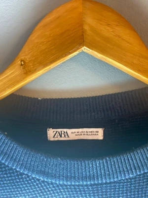 Mörkblå stickad tröja från Zara - Mörkblå stickad tröja från Zara med rund halsringning och lång ärm. Tröjan har en enkel, klassisk design och är tillverkad i ett mjukt, strukturerat material som passar perfekt till höst och vinter.