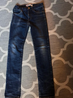 Mörkblå jeans från Levi's - Säljer ett par mörkblå jeans från Levi's med klassisk femficksmodell. Jeansen har snygga slitningar och kontrastsömmar, samt den ikoniska läderlappen bak i midjan. Perfekta till en avslappnad stil och tillverkade i mjuk bomullsdenim. Med några sjusta fades fast dem ser man inte passar dig som är ungefär 160 och 4 centimeter uppåt och 7 neråt ä slim ifall su ö 155 och mindre å skinne ifall du ör mellan 160-168 