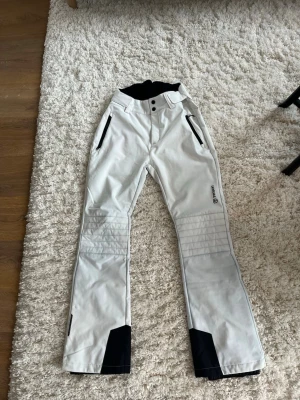  Vita skidbyxor från tenson - Snygga vita bootcut skidbyxor från tenson. Använda en gång. Fleece inuti så dom är varma och sköna, finns så man kan dra åt i midjan 
