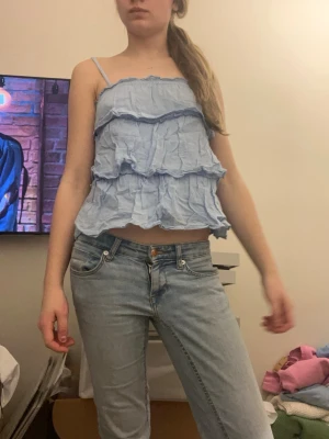 Ljusblå volang linnetopp - Säljer en ljusblå linnetopp med flera volanger och tunna axelband. Andvänt 2 gånger ich köpt från Gina Tricot storlek Xs