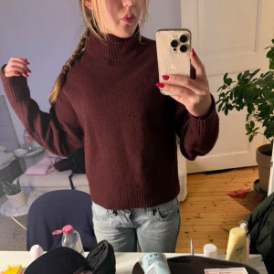 Mörkröd stickad tröja med hög krage - Säljer en mörkröd stickad tröja med hög krage och ribbade muddar. Tröjan har en avslappnad passform och långa ärmar. Pris kan diskuteras vid snabb affär💓