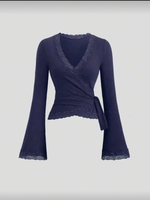 Mörkblå omlottopp med spetsdetaljer - !!HELT NY BARA TESTAD!! Trendig mörkblå omlottopp med långa utsvängda ärmar och fina spetsdetaljer vid halsringning, ärmslut och nederkant. Toppen knyts i sidan för en deffad siluett och har en snygg v-ringning. Perfekt från skolan till stan!
