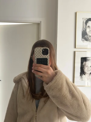 Beige teddyjacka med huva från zara - Mysig teddyjacka i beige färg med huva och dragkedja framtill. Jackan är i 13-14 år och är i jättebra skick och är superskön. Den är använd ungefär 6 ggr
