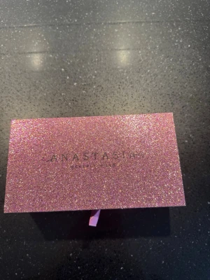 Anastasia Sultry ögonskuggspalett - Säljer en Anastasia Beverly Hills Sultry ögonskuggspalett med glittrigt bronsfärgat fodral. Paletten har en lyxig känsla och är perfekt för dig som gillar glam och shimmer. Förpackningen är rektangulär och täckt av glitter som verkligen sticker ut.