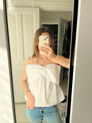 Vit topp med rosett - Jätte fin topp från Kappahl. Helt ny och aldrig använd, skit snygg till sommarn!