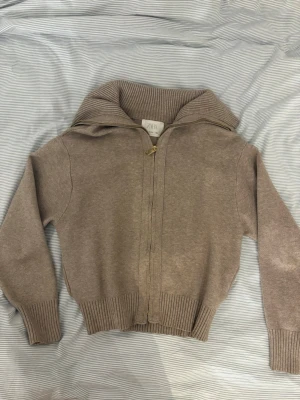 Beige ziptröja med krage från Zara - Snygg beige ziptröja från Zara med bred ribbad krage och ribbade muddar. Tröjan har hel dragkedja framtill och är tillverkad i mjukt stickat material. Perfekt för att skapa en avslappnad och trendig look.