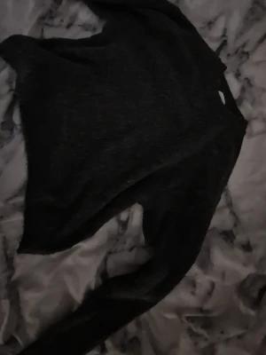 Svart stickad tröja med rund hals - Mysig svart stickad tröja med rund hals och långa ärmar. Tröjan har en enkel och stilren design som passar perfekt till många olika outfits. Materialet ser ut att vara mjukt och bekvämt.