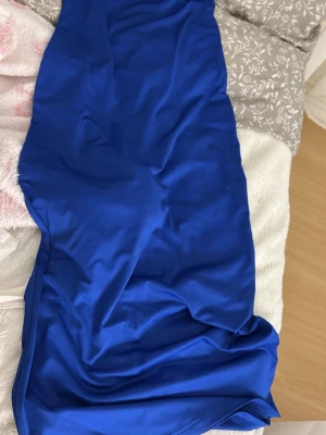 Lång blå klänning i polyester - Snygg långklänning i klarblå färg med enkel och stilren design. Klänningen är ärmlös och har en smal passform som framhäver siluetten. Tillverkad i mjukt och följsamt polyestertyg som ger en skön känsla.