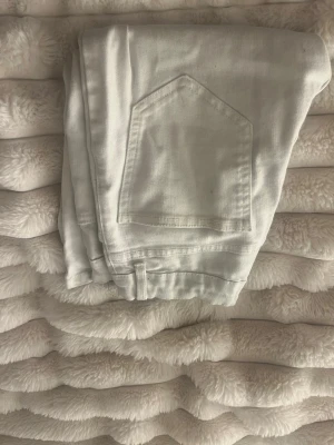 Vita raka jeans - Säljer ett par vita jeans med rak passform och klassiska bakfickor. Jeansen har en enkel och stilren look, perfekta att matcha med olika outfits. Materialet känns mjukt och bekvämt, troligtvis bomull eller bomullsblandning. Inga synliga loggor eller märken.