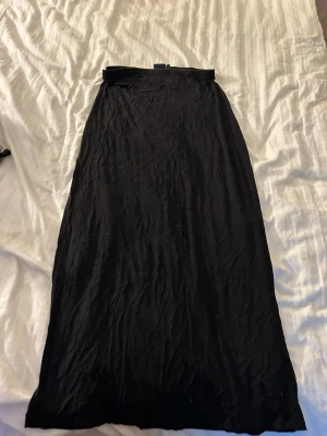 Svart långkjol i mjukt material - En enkel och stilren svart långkjol med rak passform. Kjolen är gjord i ett mjukt och lätt material som faller snyggt. Perfekt att matcha med en crop top eller stickad tröja för en chill look.