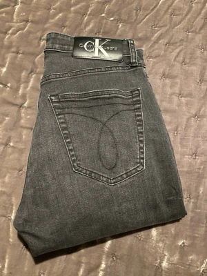 Mörkgrå jeans Calvin Klein - Snygga mörkgrå jeans från Calvin. Jeansen har en broderad CK-logga och är tillverkade i mjukt denim tyg. Passform: modern taper