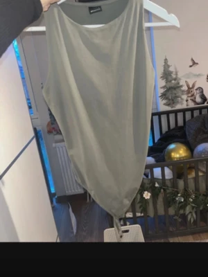 Grön ärmlös linnetopp Gina Tricot - Snygg grön ärmlös linnetopp från Gina Tricot. Toppen har en enkel och stilren design med rund halsringning och mjukt material som känns skönt mot huden. Perfekt att matcha med jeans eller kjol för en trendig look.