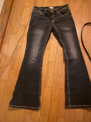 Svarta bootcut jeans med vita sömmar - Säljer ett par gråa bootcut jeans med snygga vita sömmar. Jeansen har klassisk femficksmodell och låg midja. Perfekta för dig som gillar retrostil och vill sticka ut lite extra. Från Gina Tricot 14+. 