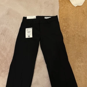 Svarta kostymbyxor från Bershka - Stilrena svarta kostymbyxor från Bershka med klassisk rak passform och hällor för skärp. Aldrig användA