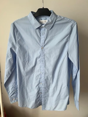 Ljusblå skjorta från Pier one - Klassisk ljusblå skjorta från Pier One med krage och knappar framtill. Skjortan har lång ärm och är tillverkad i mjuk bomull, perfekt för en clean och stilren look.