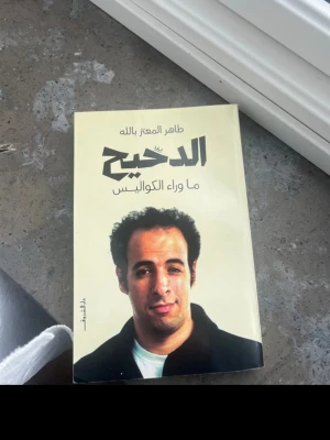 Boken الدحيح - ما وراء الكواليس - Säljer en skönlitterär bok med ljusgul framsida och arabiska titeln الدحيح - ما وراء الكواليس. Boken har ett porträtt på omslaget och är skriven av طاهر المعتز بالله. Perfekt för dig som gillar berättelser och kultur.