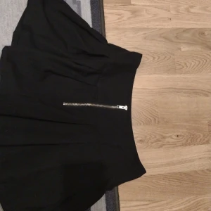 Svart kortkjol med dragkedja - Snygg svart mini skirt med en stilren dragkedja där framme. Perfekt för både vardag och fest! Kjolen har en enkel design som gör den lätt att matcha med olika toppar och accessoarer. Ett måste i garderoben för alla som älskar klassiska plagg. Storlek 158-164 alltså S. För mer info kontakta gärna mig 💕