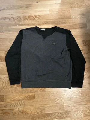 Mörkgrå sweatshirt från Dolce & Gabbana - Snygg mörkgrå sweatshirt från Dolce & Gabbana med svarta ärmar och diskret logopatch på bröstet. Tröjan har rund halsringning och ribbade muddar vid ärmslut och nederkant. Perfekt för en stilren och avslappnad look.