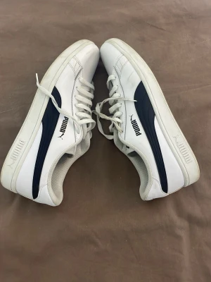 Vita Puma sneakers med svart detalj - Snygga vita sneakers från Puma med klassisk svart sidodetalj och logga på både plös och häl. (Utan paket) ,Skick 8/10, vid frågor så kan ni höra av er via Dm🤝