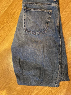 Blå Weekday Space Relaxed Straight Jeans - Säljer ett par blå jeans från Weekday i modellen Space Relaxed Straight Jeans. Jeansen har rak passform och klassisk femficksdesign. Tillverkade i slitstarkt denimtyg, perfekta för en avslappnad och trendig look.