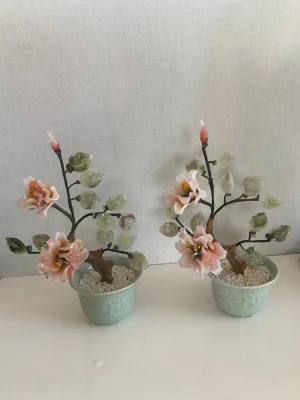 Dekorativa blommor i glas, 2 st - Två konstgjorda blomsterarrangemang i glas med rosa blommor och gröna blad. Blommorna står i ljusgröna krukor fyllda med vita stenar. Perfekt som prydnad till hemmet för en elegant och unik touch.