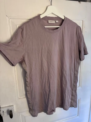 Beige t-shirt från Calvin Klein Jeans - Säljer en stilren beige t-shirt från Calvin Klein Jeans. T-shirten har rund halsringning, korta ärmar och diskret logga tryckt på sidan. Tillverkad i mjuk bomull som känns skön mot huden. Perfekt för en avslappnad och trendig look. Passar L/XL