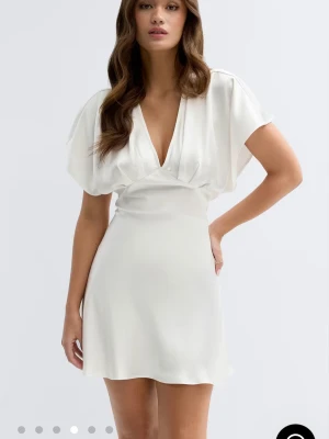 Satin minidress ginatricot - Kort vit klänning i ett mjukt, glansigt material med v-ringning och vida korta  Perfekt för sommarens alla tillfällen.