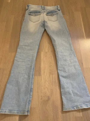 Ljusblå bootcut jeans med fickdetaljer - Säljer ett par ljusblå bootcut jeans med snygga fickdetaljer bak. Jeansen är midwaist och i storlek 158.
