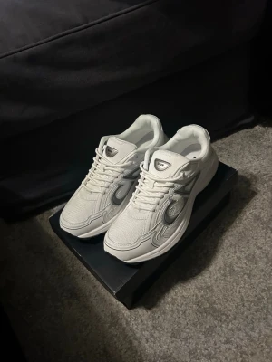 B30 skor vita - Snygga vita b30 sneakers med mesh och läderdetaljer samt silverfärgade inslag på sidorna. Klassisk chunky sula och logga på plösen. Perfekta för dig som vill ha en clean och exklusiv look.