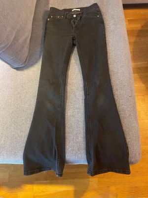 Svarta bootcut jeans med hög midja - Snygga svarta bootcut jeans medmedel hög midja och klassiska fem fickor. Jeansen har utsvängda ben, de har några små fläckar och en orange färgfläck som inte går bort😔 (pris kan diskuteras☺️)