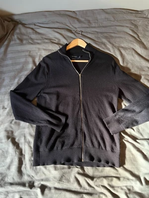 Svart merinoullströja från Riley - Snygg svart tröja från Riley i mjuk merinoull.  Storlek är M och modell är 182 cm och väger 72 kg. Inga defekter och finns en exakt lika dan fast i grå uppe! Mitt pris 399!