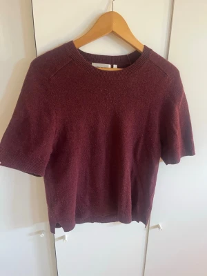 Vinröd kortärmad tröja Carin Wester - Vinröd stickad tröja från Carin Wester med korta ärmar och rund halsringning. Tröjan har ribbade muddar vid hals, ärmslut och nederkant. Perfekt till lager på lager och enkel att styla till olika looks.