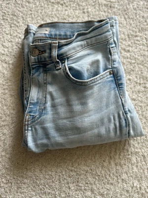 Ljusblå jeans från Perfect Jeans - Säljer ett par ljusblå jeans från Perfect Jeans i storlek 36. Jeansen har klassisk femficksmodell, normalhög midja och snygga slitningar för en trendig look. Materialet är mjukt denim med lite stretch för extra komfort. De säljs inte längre på ginas hemsida, original pris 500kr.