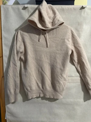 Kashmir hoodie - Säljer en stilren beige hoodie i mjuk och skön kashmir . Hoodien har dragsko i huvan och ribbade muddar vid ärmslut . Perfekt för dig som gillar en enkel men snygg look. Passar till det mesta och är superbekväm. Hoodien är i storlek M men passar nog small bättre. 