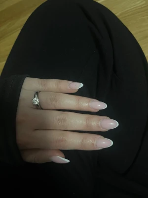 Ring med stor klar sten - Snygg silverfärgad ring med en stor, rund klar sten i mitten som ger en elegant och klassisk look. Ringen har en enkel och stilren design som verkligen framhäver stenen. Perfekt för dig som gillar tidlösa smycken med lite extra bling. Stämpel ”TI DQCZ” stl 16