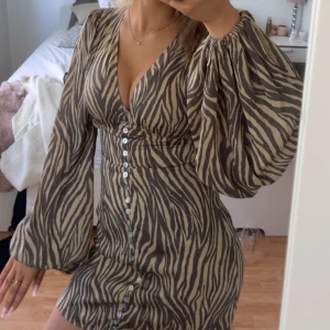 Adoore klänning - Supersnygg kortklänning från Adoore med zebramönster i beige och brunt. Den är endast använd en gång! Kan tänka mig att byta mot en annan adoore klänning i strl 36(pris går att diskutera)