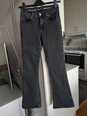 Jeans Bik Bok low, flare S - Snygga svarta jeans med low waist och flare-modell, midja i storlek S. Jeansen har klassisk femficksdesign och längd 31. Köpta på Bik Bok. Materialet är mjukt denim som ger en avslappnad men trendig look. Litet slitage längst ner på vänster ben baktill, se bild 4..