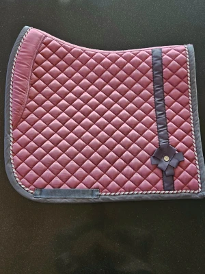 PS of Sweden limited edition schabrak  - Säljer detta superfina dressyrschabraket från PS of Sweden! Schabraket är rosa med en grå rosett, den har en fin detaljerad ytterkant och överst står det "Eat, sleep, ride repeat". Som sagt är schabraket limited edition och går inte längre att hitta, därav lite högre pris. Mycket sparsamt använd och i superfint skick, pris går att diskuteras 💕 Storlek Cob