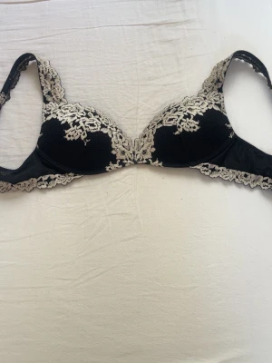 Svart intimissmi bh med spetsdetaljer - Elegant svart bh med vacker beige spets längs kuporna och axelbanden. Bh:n har vadderade kupor och fina spetskanter som ger en lyxig känsla. Perfekt för dig som gillar romantiska och feminina underkläder💞🪩// pris kan diskuteras