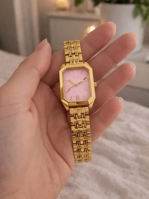 Elegant Guldig klocka med rosa urtavla - Snygg klocka med rektangulärt guldigt metallarmband och rosa urtavla. Klockan har minimalistiska visare och index, samt en unik länkdesign på armbandet. Perfekt accessoar för dig som vill sticka ut med färg och stil.